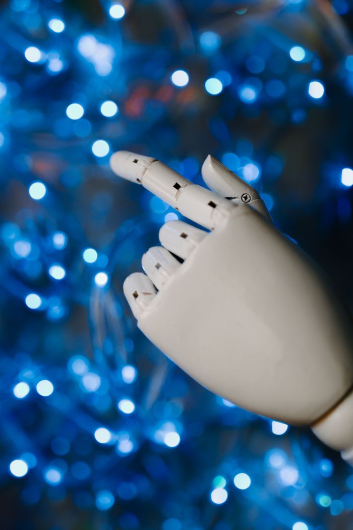 services-06 Close-up of a robotic hand with glowing blue bokeh background, symbolizing advanced technology.